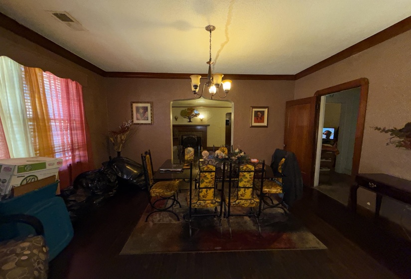 Dining area featuring dark wood-finish flooring, a chandelier with frosted glass shades, and an arched doorway opening to an additional room