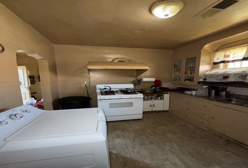 Compact kitchen featuring a gas range, stainless steel sink, wood cabinetry, and a subway tile backsplash