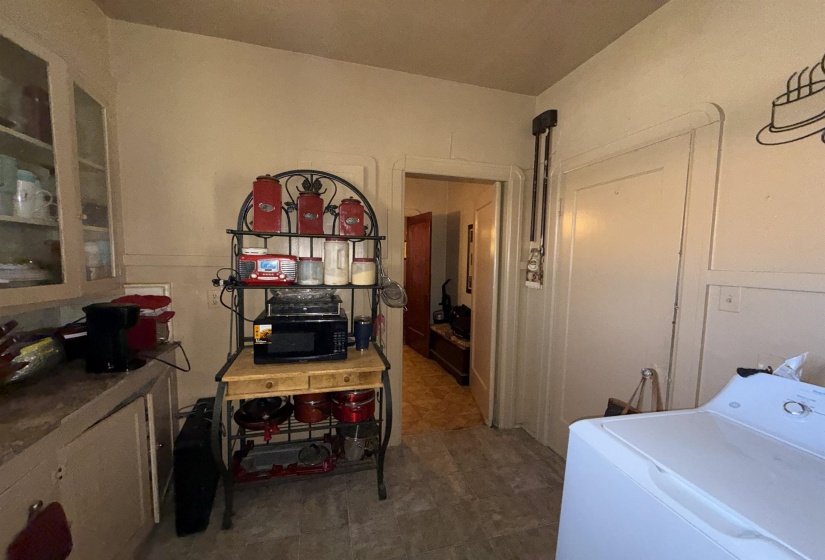 Kitchen area featuring built-in cabinetry with glass-front uppers, a countertop, and durable flooring