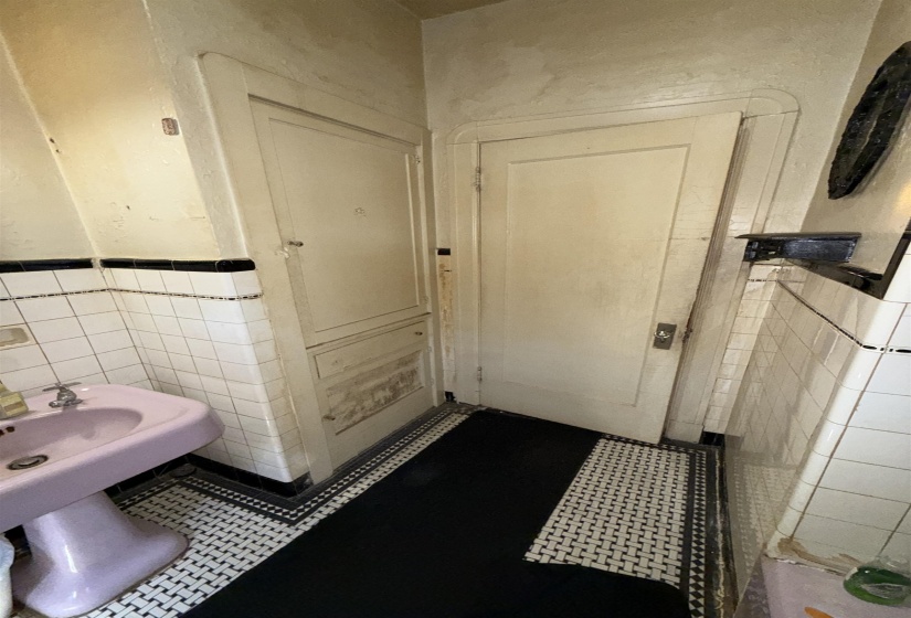 Bathroom featuring a lilac pedestal sink, white subway tile walls with black trim, and a black and white mosaic tile floor