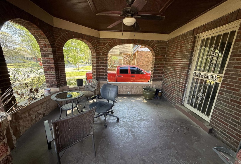 Inviting covered front porch featuring brick arches, a paneled wood ceiling, and a ceiling fan