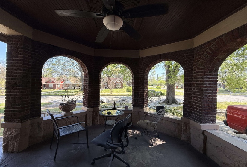 Covered porch featuring brick archways, a wood-finish beadboard ceiling, a ceiling fan with integrated lighting, and a stone-finish knee wall