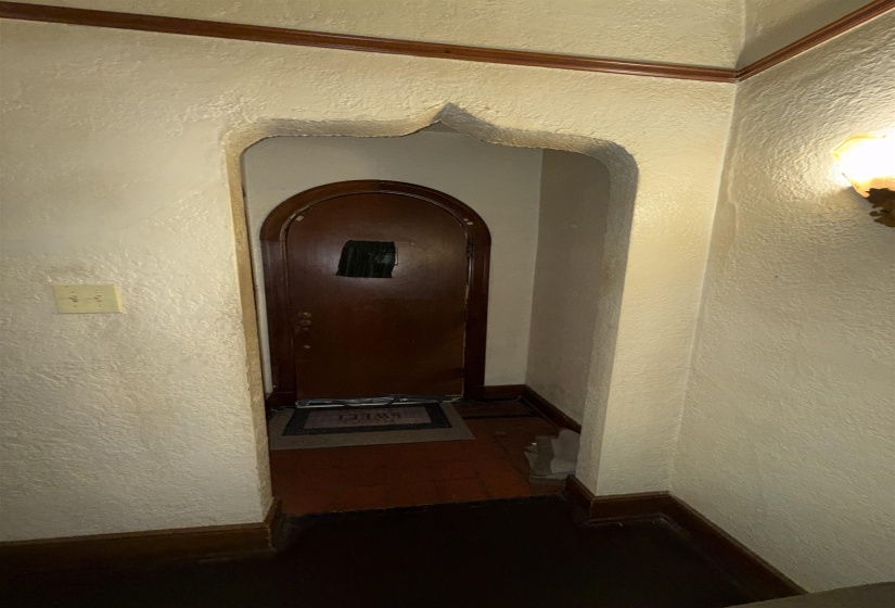 Archway entry featuring a decorative trim, textured wall finish, and a dark wood-finish door