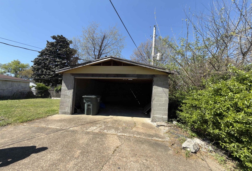 Detached block garage with an open bay and concrete pad