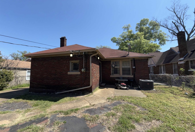 Brick exterior structure featuring a brown shingle roof, a window with exterior sill, and a patio area