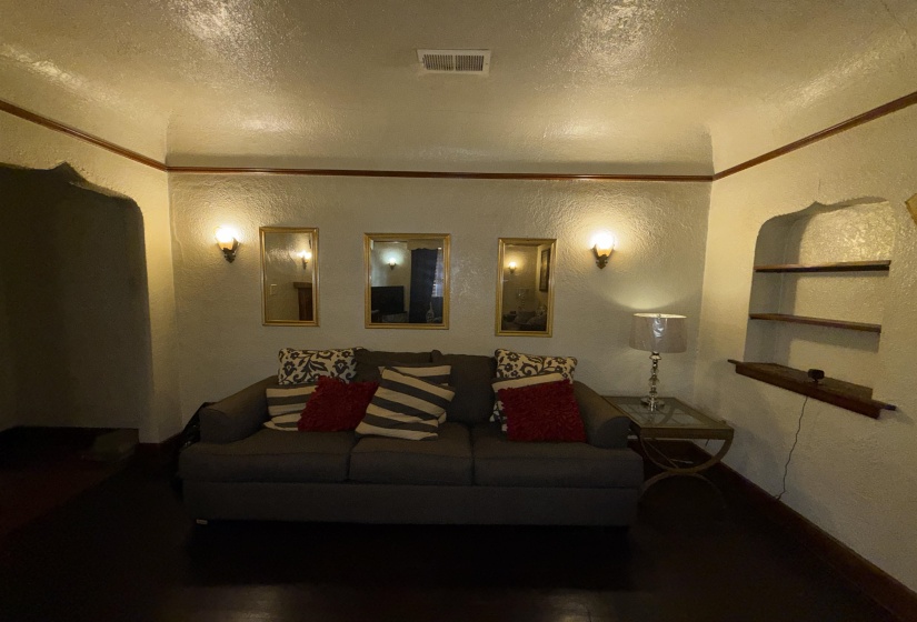 Living area featuring dark wood-finish flooring, textured walls, and decorative ceiling trim