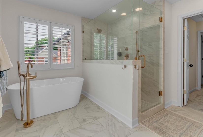 Freestanding soaking tub with a floor-mounted brass fixture