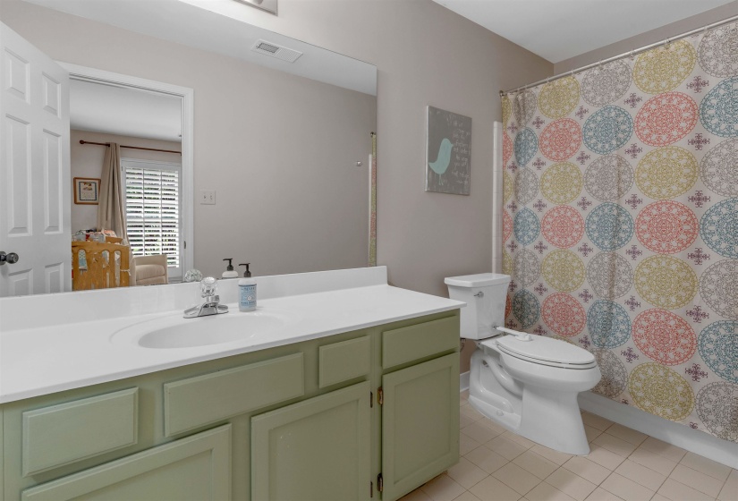 Bathroom featuring a pale green vanity with an integrated white sink and a white countertop
