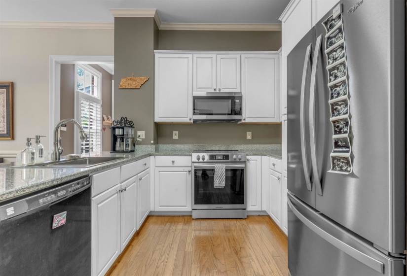 Kitchen with white cabinetry, granite countertops, and wood-finish flooring