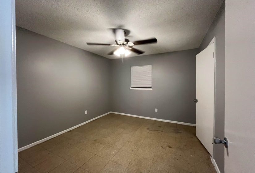 Empty room with a ceiling fan, a textured ceiling, and tile patterned floors