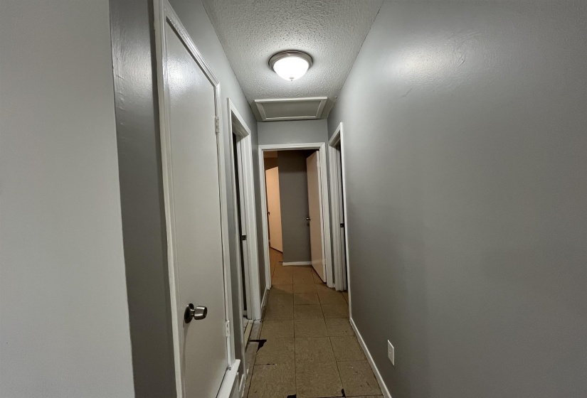 Corridor featuring a textured ceiling and attic access