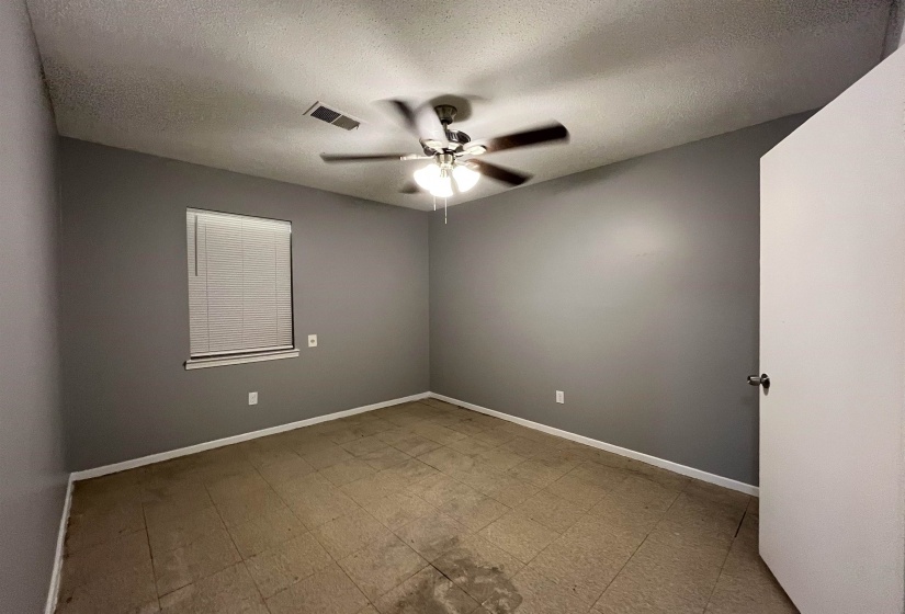 Empty room with a ceiling fan, a textured ceiling, and tile patterned floors