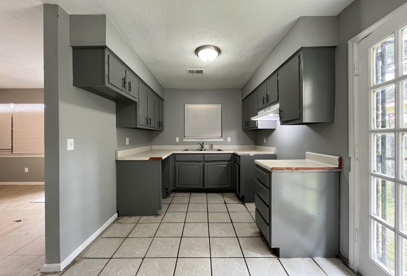 Kitchen featuring under cabinet range hood, a textured ceiling, plenty of natural light, gray cabinets, and light countertops