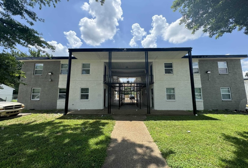 Two-story multi-unit building featuring a central breezeway, exterior walkways, and a covered entry