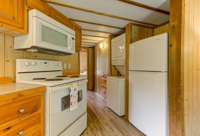 Kitchen featuring wood-finish cabinetry, solid surface countertops, and white appliances including a range with an overhead microwave