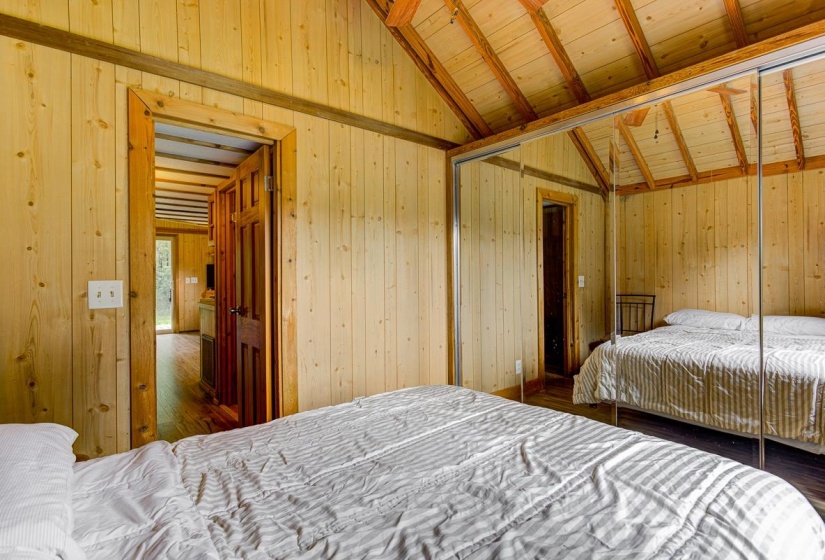 Sliding mirrored closet doors reflecting the vaulted wood-finish ceiling with exposed beams