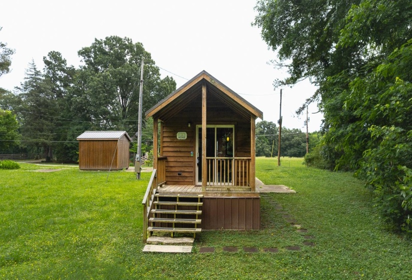 Wood-sided cabin featuring a covered porch, sliding glass door entry, and wooden steps