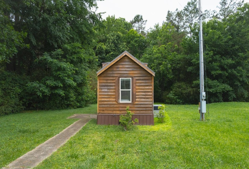Wood-sided structure with a gabled roof and white-framed window
