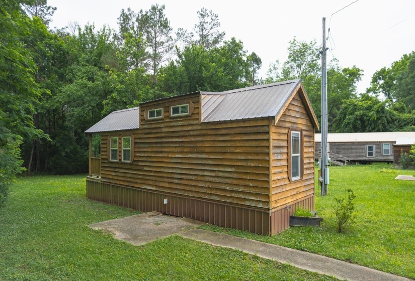 Wood-sided dwelling featuring a metal roof, dormer windows, and a covered porch entry