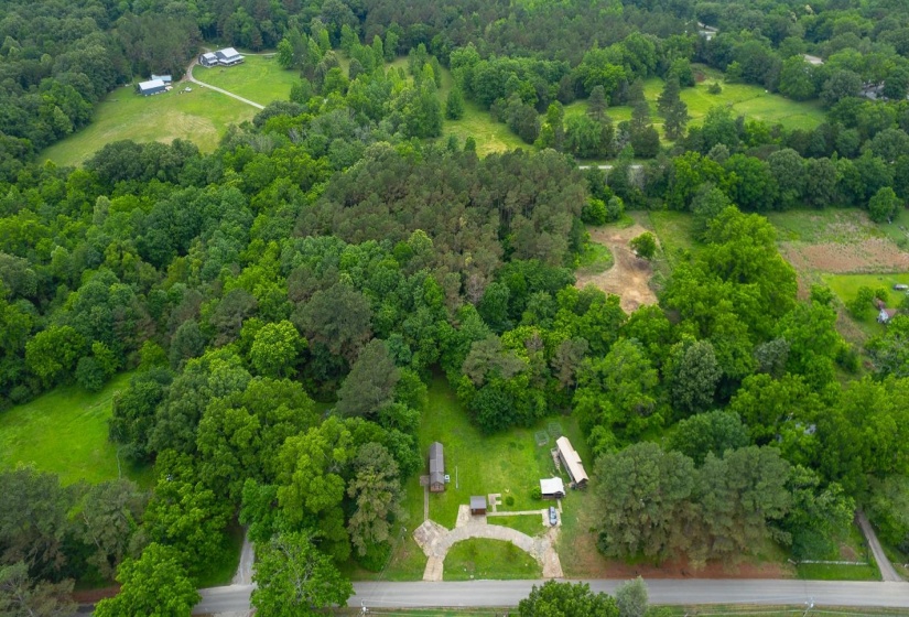 Expansive acreage featuring mature trees, a cleared field, and a paved road
