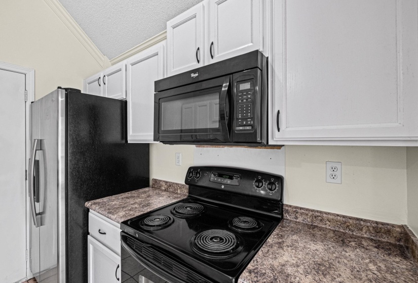 Kitchen featuring white cabinetry with dark hardware, a black over-the-range microwave, and a black electric range