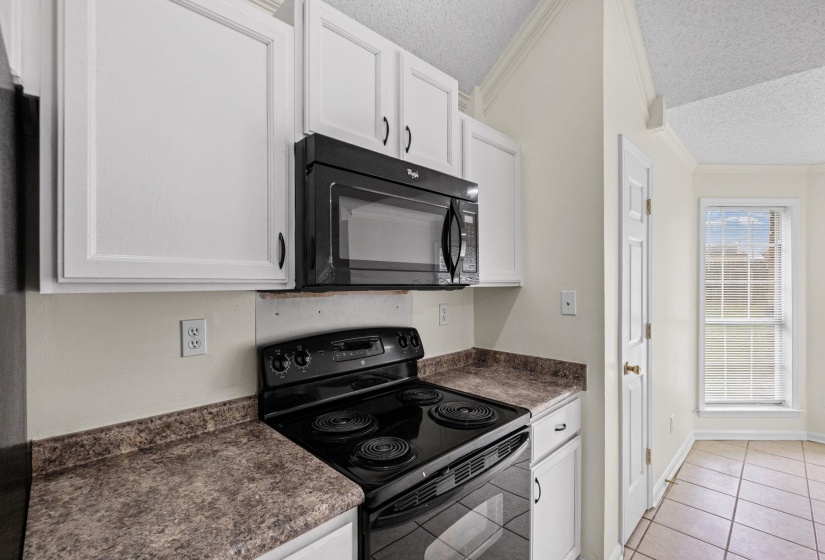 Kitchen featuring white cabinetry with dark hardware, a black electric range, and a black built-in microwave