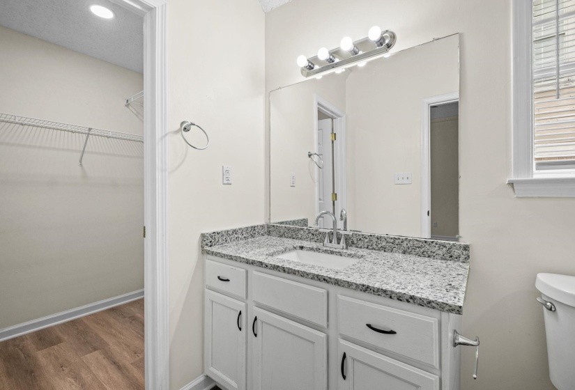 Bathroom vanity featuring a speckled countertop, undermount sink, and chrome faucet