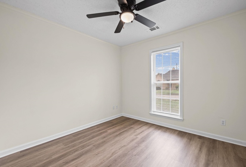 Room featuring wood-finish flooring, a ceiling fan with integrated lighting, and a double-hung window with blinds