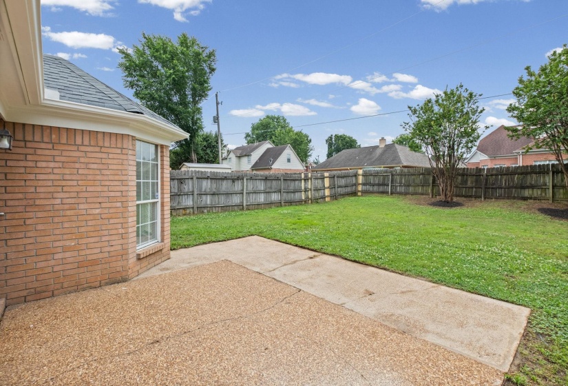 Expansive backyard featuring a large concrete patio, a privacy fence, and a manicured lawn