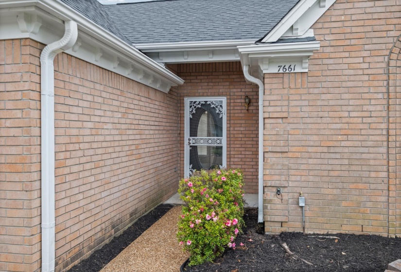Brick exterior featuring a gray shingle roof, white gutters, and white soffit