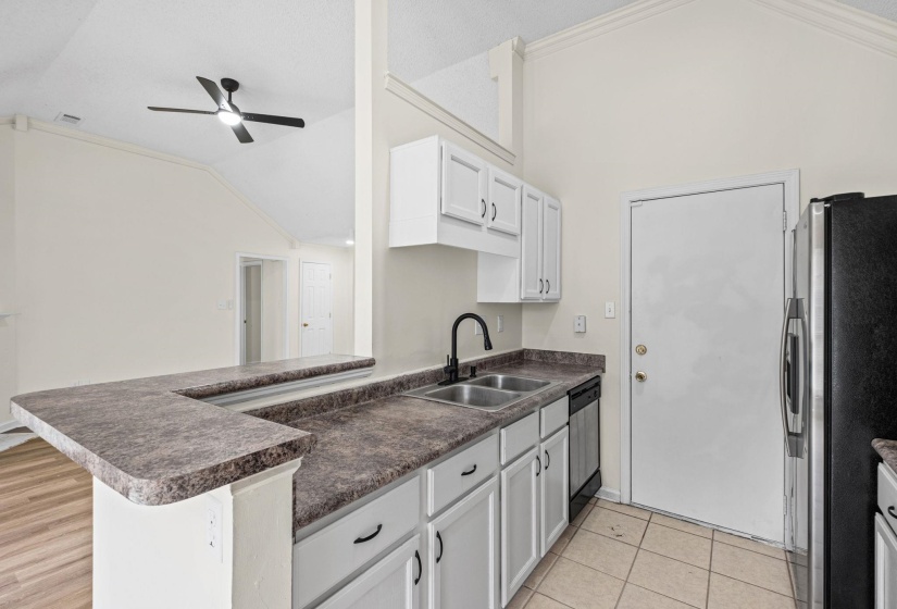Kitchen featuring white cabinetry, dark countertops, a double basin sink with a matte black faucet, and stainless steel appliances