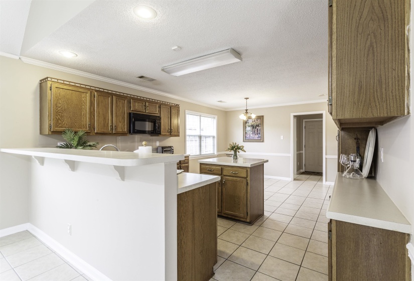 Kitchen featuring wood cabinetry, light countertops, tile flooring, a built-in microwave, and recessed lighting