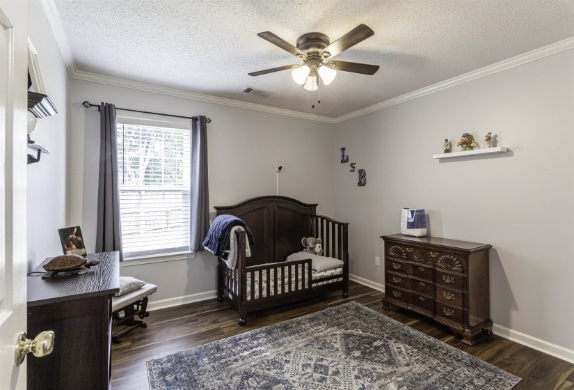 Room featuring wood-finish flooring, crown molding, and a ceiling fan with integrated lighting
