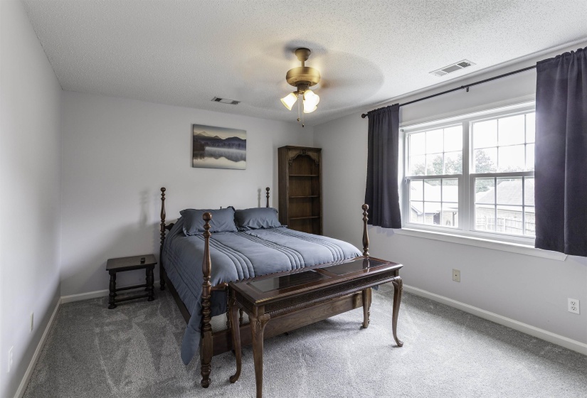 Bedroom featuring plush grey carpeting, white walls, a multi-pane window, and a ceiling fan with integrated lighting