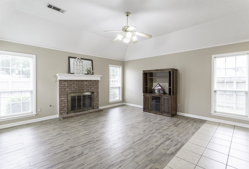 Living space featuring a brick fireplace with a white mantel, high vaulted ceilings, and a ceiling fan