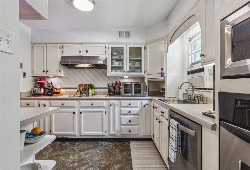 Kitchen featuring white cabinetry, a tile backsplash, stainless steel appliances, a double basin sink with a gooseneck faucet, and ample counter space