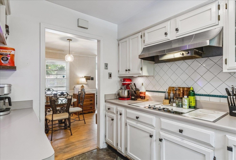 Kitchen featuring white cabinetry, light-toned countertops, a stainless steel range hood, and a white diagonal tile backsplash