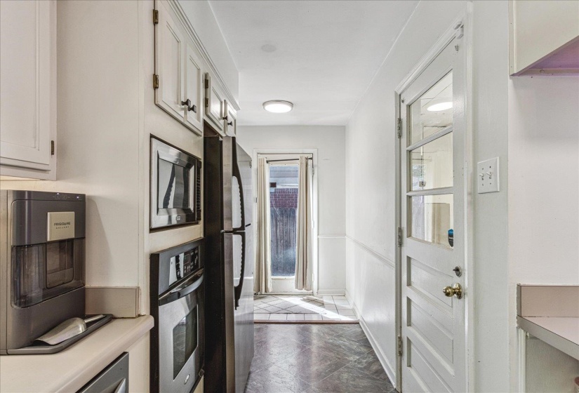 Galley kitchen featuring white cabinetry, integrated stainless steel appliances, and a glass-paneled exterior door