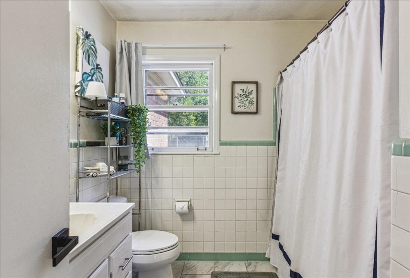 Bathroom featuring a single-pane window, white square tile wall surround, and a coordinating green trim tile