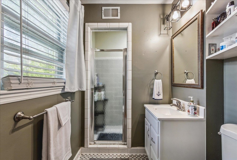 Bathroom featuring a vanity with a white countertop and basin sink, framed mirror, and built-in shelving