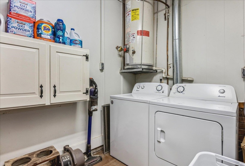 Dedicated laundry area featuring a washer and dryer, wall-mounted cabinetry with dark hardware, and a water heater