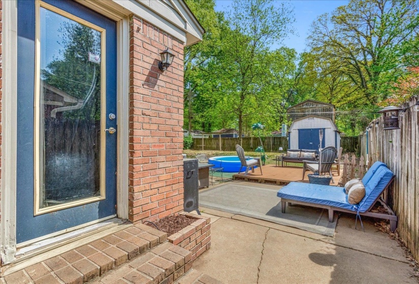 Brick exterior with a full-light door opening to a concrete patio
