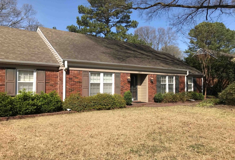 Brick exterior with brown shutters, a beige front door, and white window frames