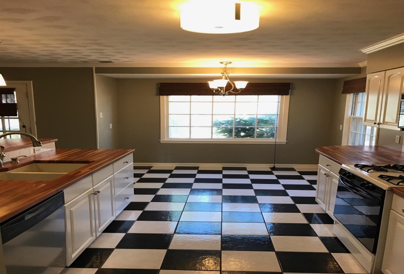 Kitchen featuring black and white checkerboard tile flooring, white cabinetry, and wood-finish countertops