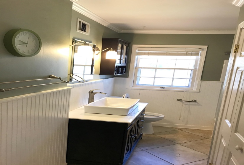 Bathroom featuring a dark wood vanity with a white vessel sink, brushed nickel faucet, and a large mirror with sconce lighting