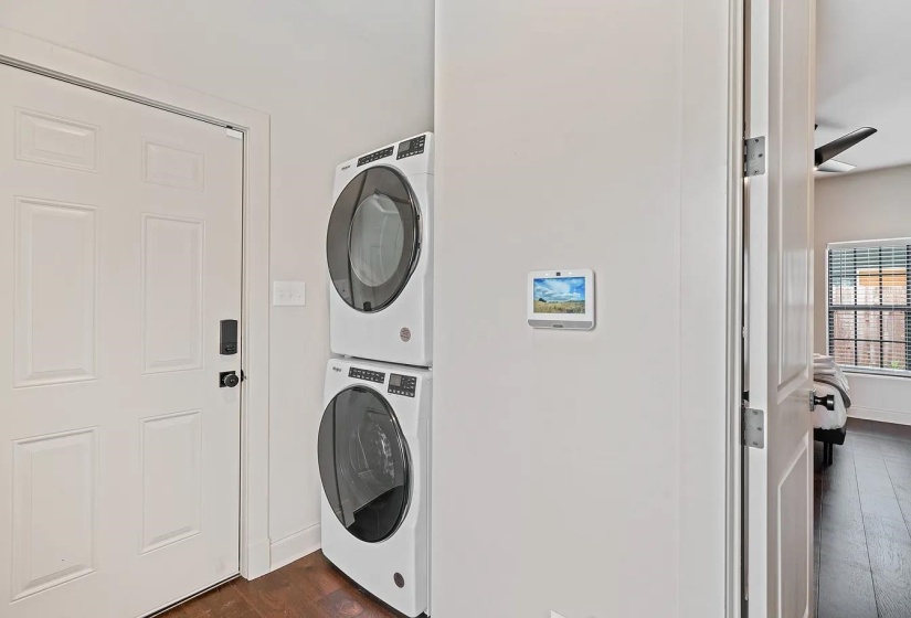 Laundry area with dark wood finished floors and stacked washer and dryer