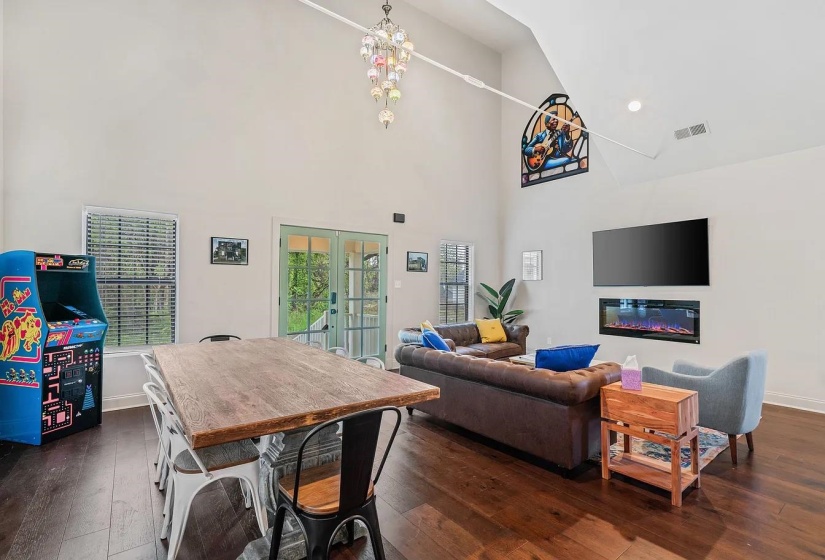 Dining space featuring french doors, dark wood-style floors, a high ceiling, and a glass covered fireplace