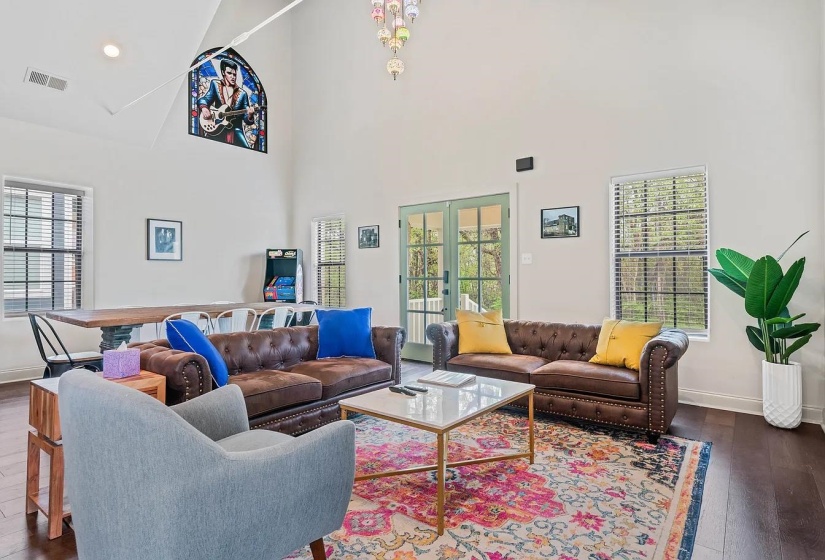 Living area with dark wood-type flooring, french doors, a high ceiling, plenty of natural light, and recessed lighting
