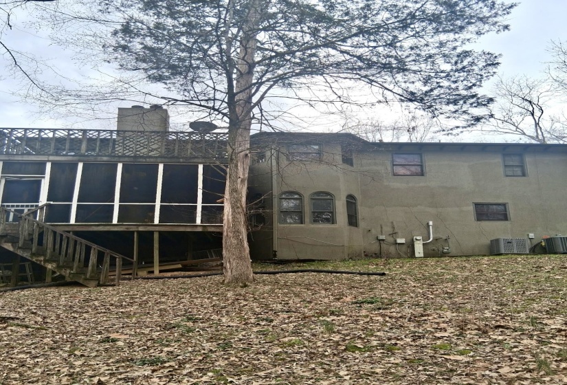 Rear view of property featuring a sunroom, a chimney, and a deck