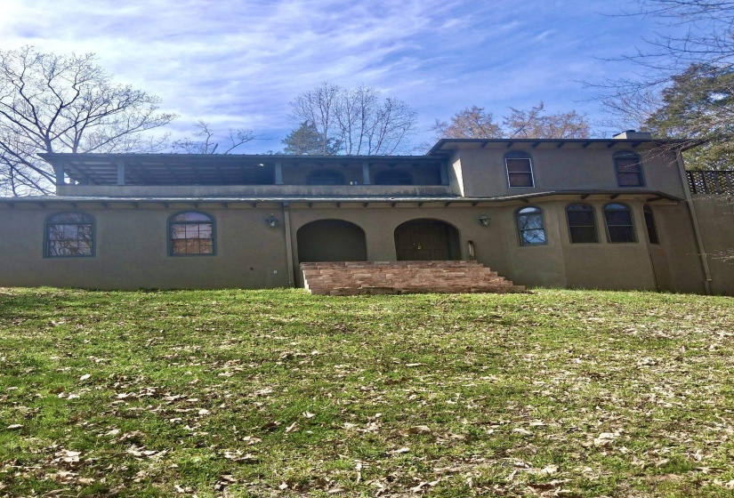Rear view of house with stucco siding and a lawn